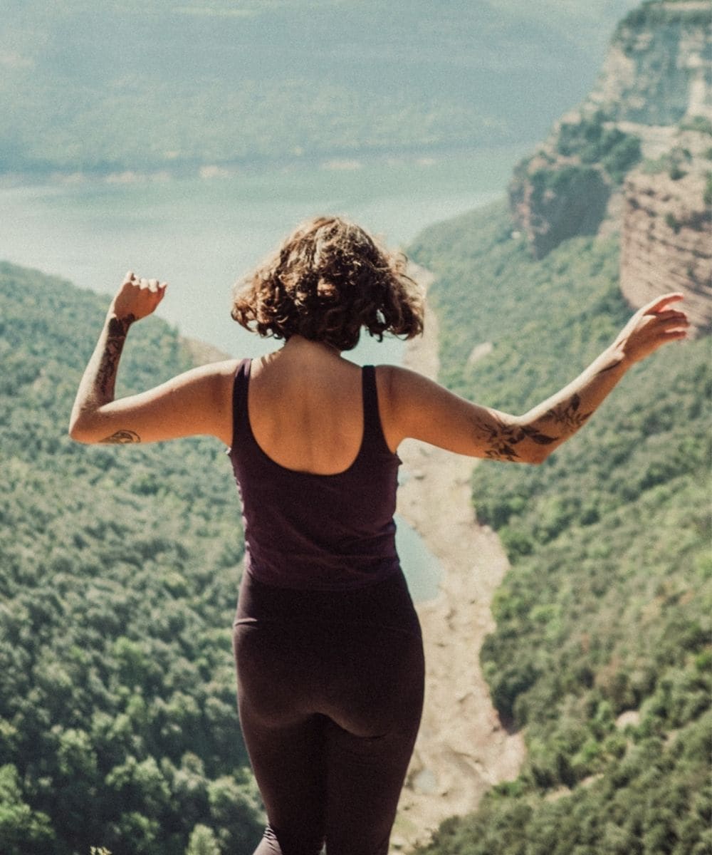 A woman standing on a cliff with her arms raised