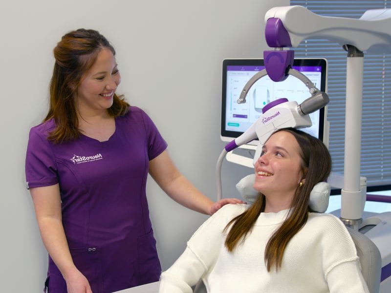 A patient smiling during a NeuroStar&reg; TMS session